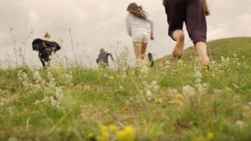 Barn springer på ett fält med sommarblommor