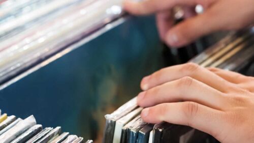 En hand bläddrar genom en hög LP-skivor