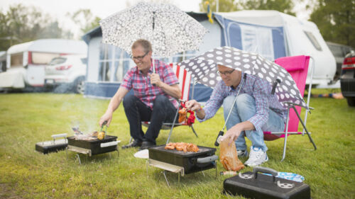 2 män som sitter under paraply och grillar
