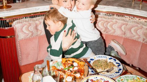 En barnfamilj skrattar vid bordet på italiensk restaurang
